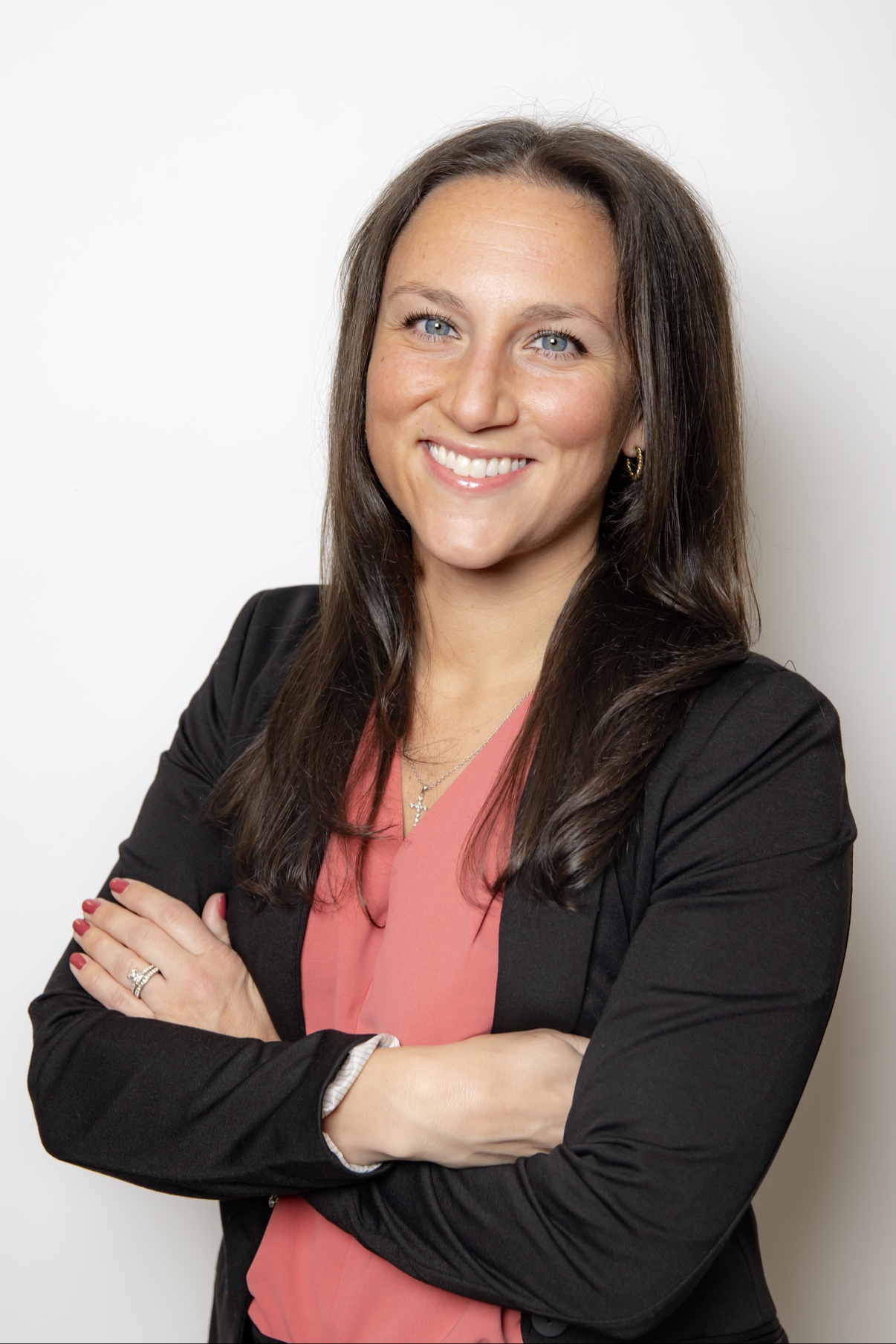 Smiling woman in a black blazer over a coral top