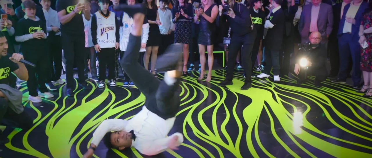 Colton’s bar mitzvah film still: guest breakdancing on a neon-patterned dance floor