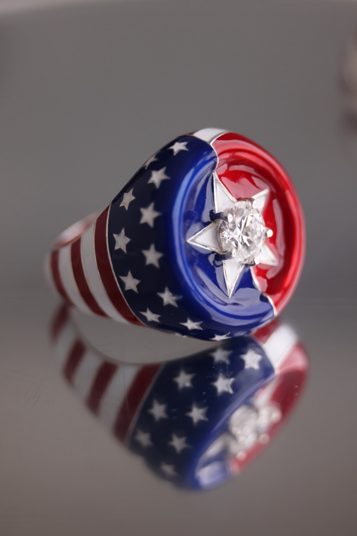 American flag enamel ring with a central diamond resting on a mirrored surface
