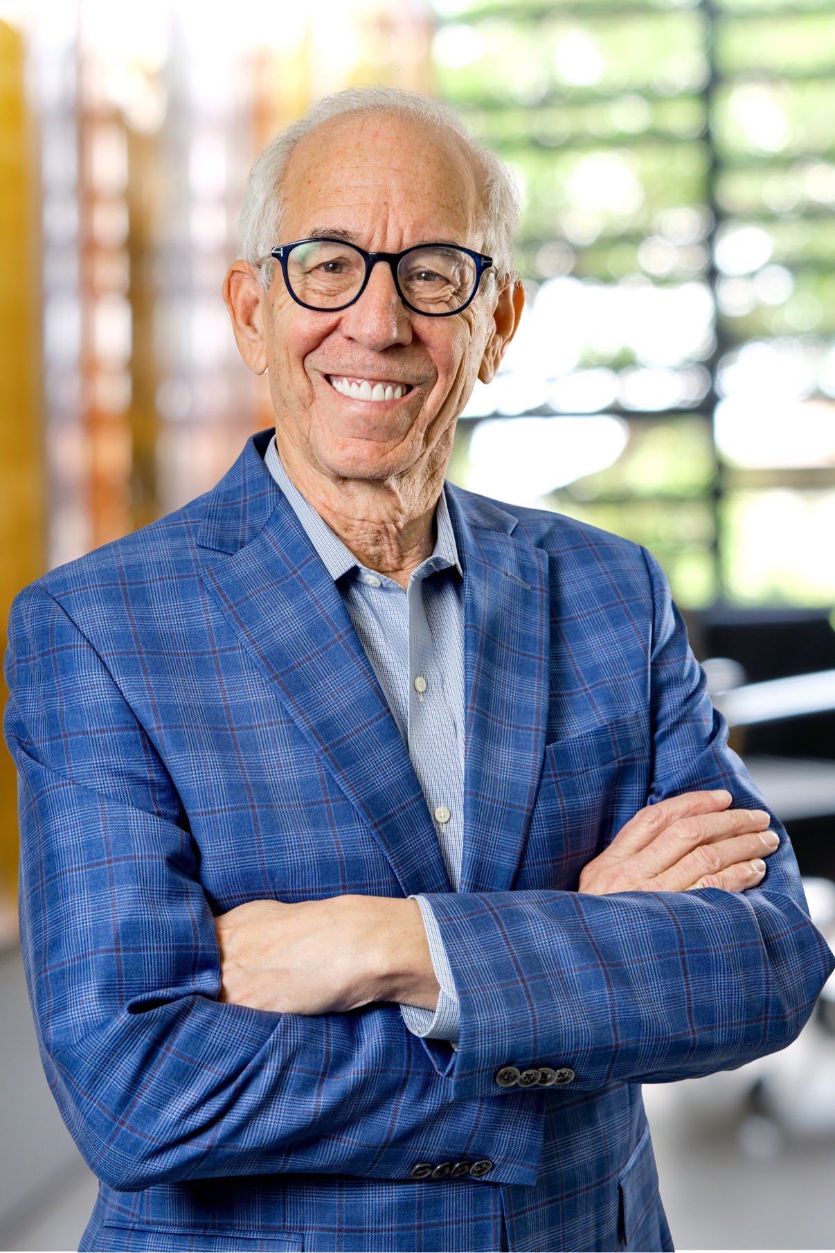 Smiling man with glasses in a blue plaid blazer
