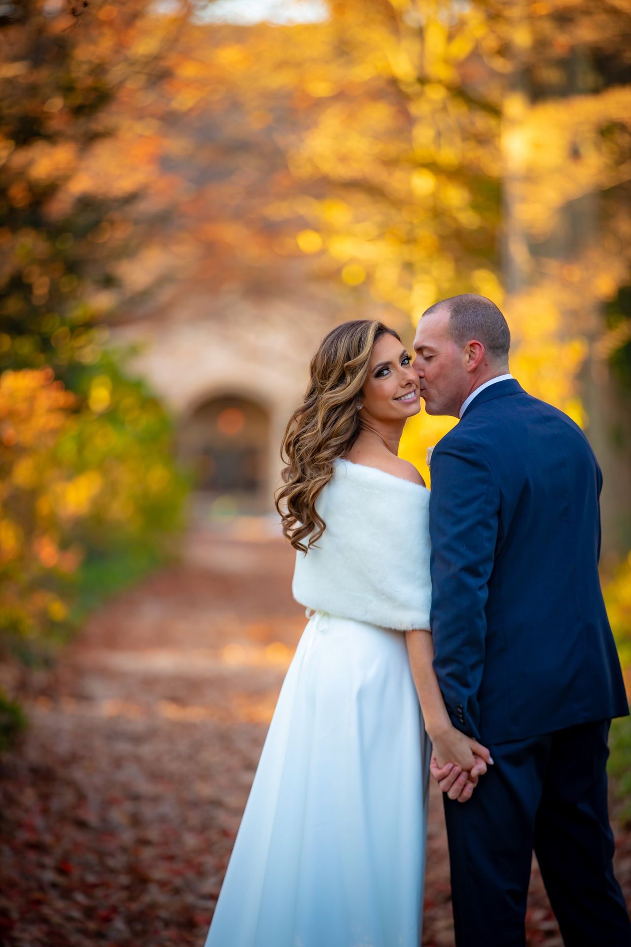 Newlyweds embracing beneath autumn trees
