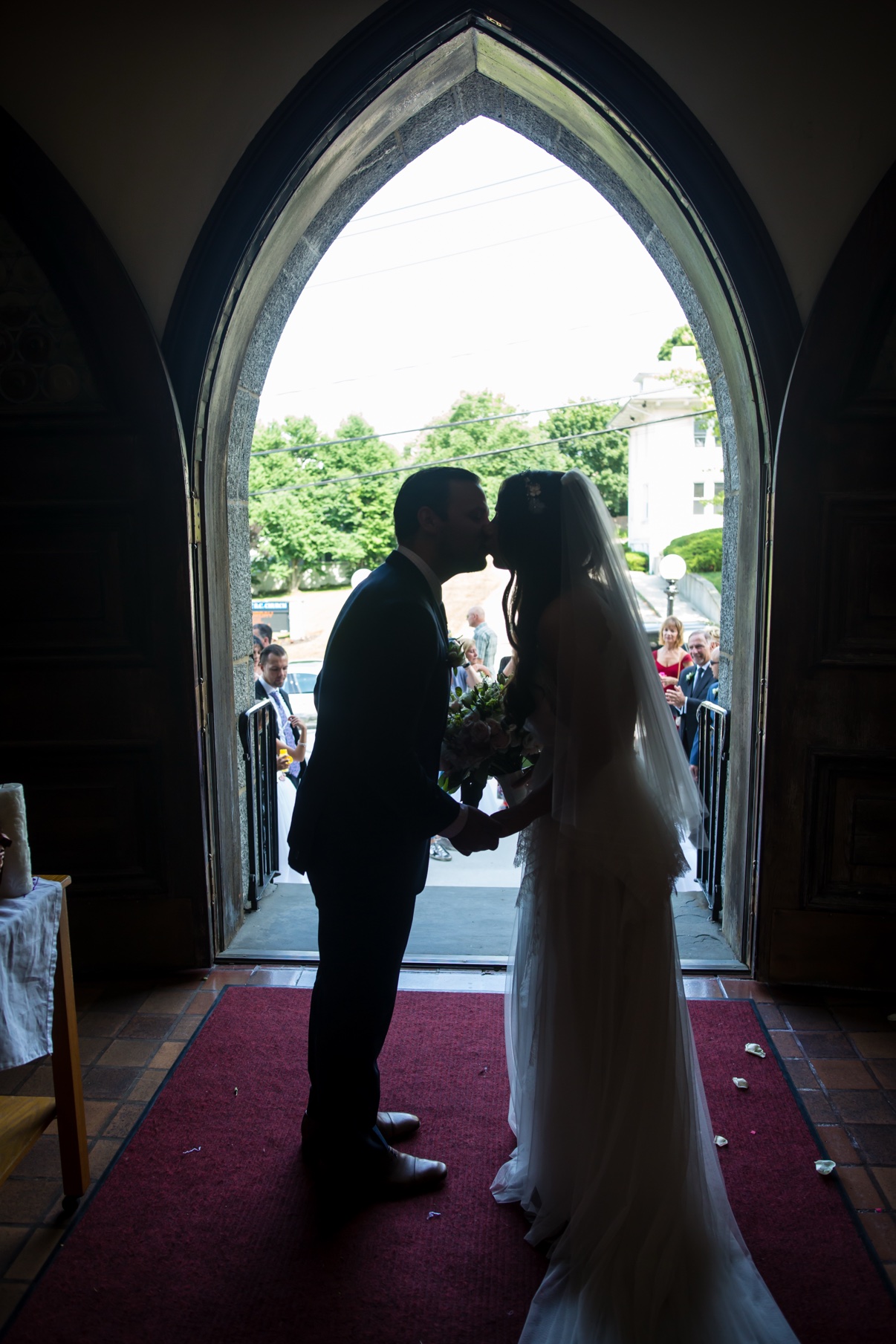 Bride and groom kissing in a church doorway