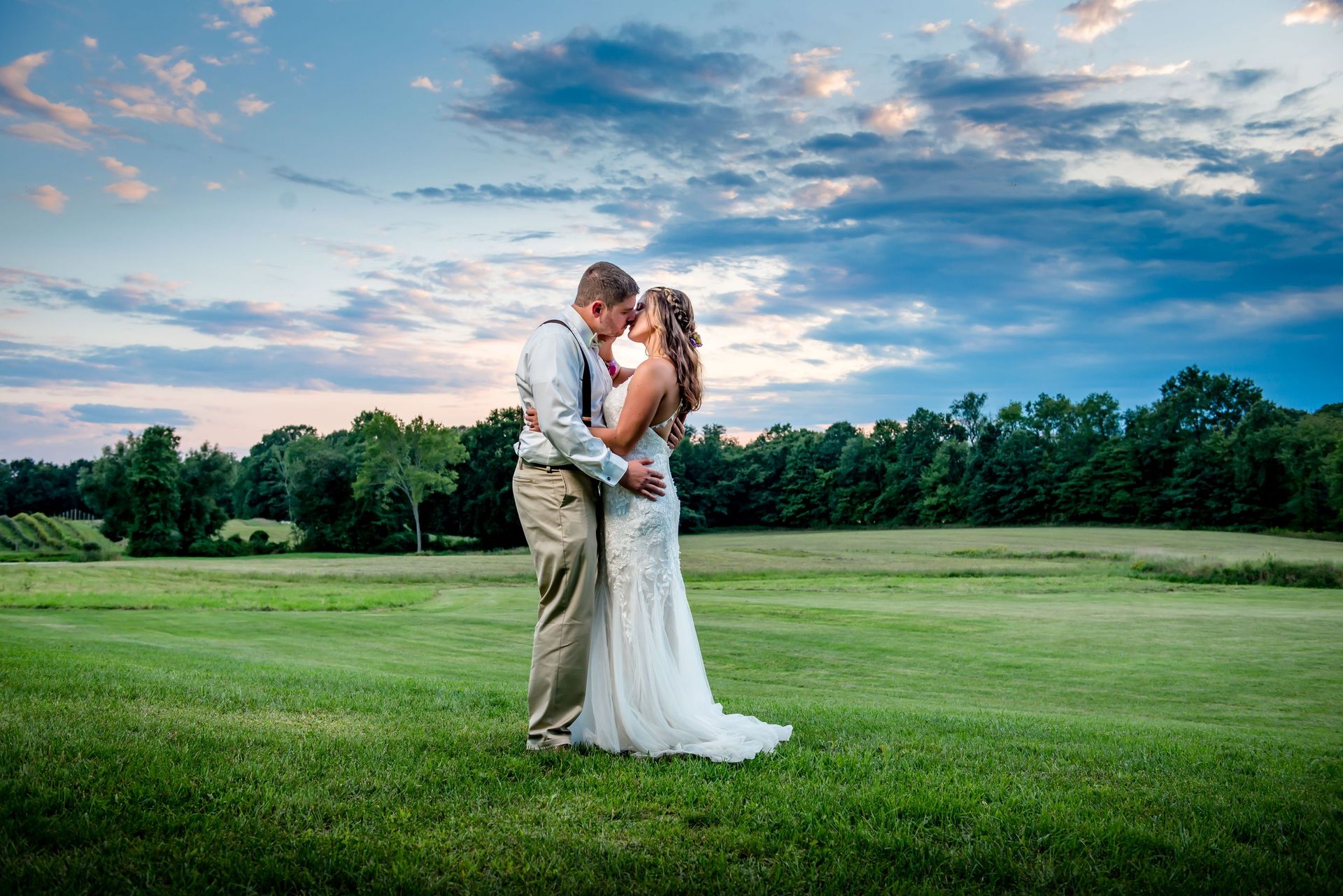 Newlyweds embracing beneath a dramatic evening sky